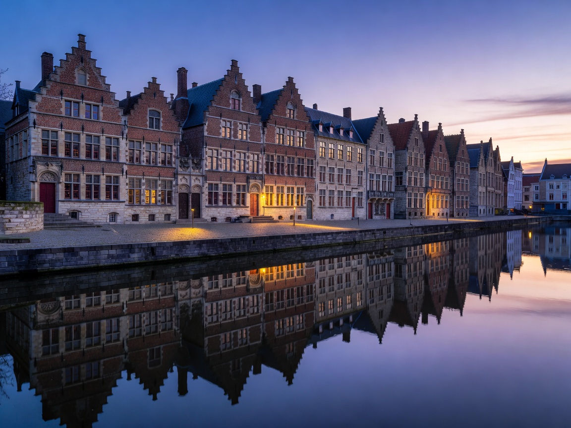 Ghent canal reflecting medieval guildhalls of Graslei at twilight